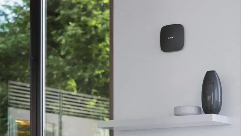 Ajax alarm hub in black on the wall of a finished living room
